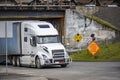 High cab white big rig semi truck transporting cargo in dry van semi trailer turning on the road under the railway bridge Royalty Free Stock Photo