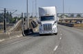 High cab white big rig semi truck transporting commercial cargo in semi trailer driving on the overpass intersection road Royalty Free Stock Photo