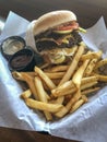 High calorie burger with french fries in a plate on a wooden table.