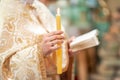 High candle burns behind a beautiful child during the baptism ceremony. The sacrament of baptism. Attributes of an Orthodox priest