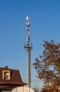 A high cell tower with antennas on top, in a city near residential buildings, against a clear sky Royalty Free Stock Photo