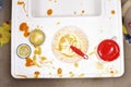 High chair with bowl spoon jar and stains of baby food view from above