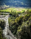 High cliff mountain waterfall and alpine valley village in background in a sunny summer day Royalty Free Stock Photo