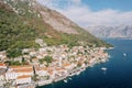 High clock tower of the Church of St. Nicholas among the red roofs of houses on the seashore. Perast, Montenegro Royalty Free Stock Photo