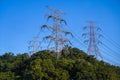 High coltage post, tower, electricity power pylon at the peak, top of mountain agaisnt blue sky