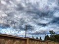 High concrete wall and fence with barbed wire on background of sky with clouds and small piece of blue sky. Protected Royalty Free Stock Photo