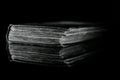 High contrast black and white image of an old book on black reflective surface Royalty Free Stock Photo