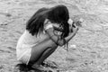 a black and white image of a woman kneeling in the water holding rocks