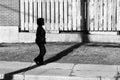 High Contrast Silhouette of a Woman Walking on a Sidewalk in Shadow