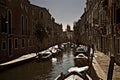 High contrast view of a canal with countless boats and walkways either side in the residential areas of touristic Venice