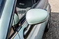 Detailed view of a passenger car seat and wing mirror of an Italian made small car on a driveway.