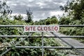 High contrast view of a Site Closed sign seen attached to a metal gate.