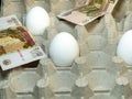 High cost. Imitation of products. Money with eggs. High price. Half-empty egg carton Royalty Free Stock Photo