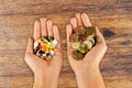 High cost of medical pills concept with piles of coins and pharmaceutical drugs in woman hands with wooden background Royalty Free Stock Photo