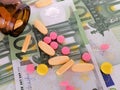 High costs of health care. Closeup of different types of pills and glass bottle on a one hundred European banknote Ã¢â¬â euro. Royalty Free Stock Photo
