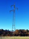 High voltage mast in picturesque rural landscape under cloudless dark blue sky Royalty Free Stock Photo