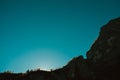 High dark scary rock canyon at sunrise with sun behind trees in italian dolomites alps mountains