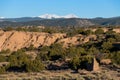 Desert red rock landscape contrasted with trees and snow-capped mountain peaks near Santa Fe, New Mexico