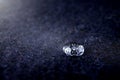 high detail close-up of sparkling drop of water on dark blue boild wool - bright light mood with deep shadows Royalty Free Stock Photo