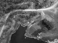 High drone aerial down onto lines formed by pipes, a road, the plant lined waters edge, and power lines