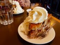 High Dutch apple pie with plenty of whipped cream on a brown wooden table with a cup of hot tea in winter Royalty Free Stock Photo