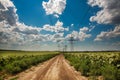 High electricity pillars on country road under blue sky clouds