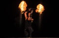 High energy firedancer. Sensual firedancer twirl flaming baton in darkness. Fire performance.