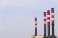 High factory exhaust pipes against a blue sky, urban air pollution