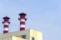 High factory exhaust pipes against a blue sky, urban air pollution