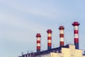 High factory exhaust pipes against a blue sky, urban air pollution