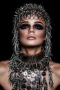 High fashion beauty model with metallic headwear and dark makeup and blue eyes on black background