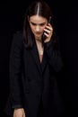 High fashion an expressive portrait of a young elegant woman in black suit who is talking on the phone