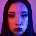 High fashion model in colorful bright neon lights. Close up portrait of beautiful girl with red lips and pierced nose Royalty Free Stock Photo