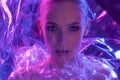 High Fashion model girl in colorful bright neon lights posing in studio through transparent film. Portrait of beautiful Royalty Free Stock Photo