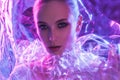 High Fashion model girl in colorful bright neon lights posing in studio through transparent film. Portrait of beautiful Royalty Free Stock Photo