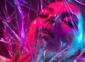 High Fashion model girl in colorful bright neon lights posing in studio through transparent film. Portrait of beautiful sexy woman