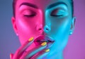 High Fashion model girl in colorful bright UV lights posing in studio, portrait of beautiful woman with trendy makeup and manicure Royalty Free Stock Photo