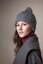 High fashion portrait of young elegant woman in studio on greyconcrete vintage wall. Grey coat and winter autumn hat Royalty Free Stock Photo