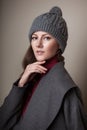 High fashion portrait of young elegant woman in studio on greyconcrete vintage wall. Grey coat and winter autumn hat Royalty Free Stock Photo