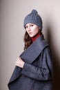 High fashion portrait of young elegant woman in studio on greyconcrete vintage wall. Grey coat and winter autumn hat Royalty Free Stock Photo