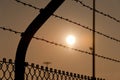 High fence with barbed wire in sunset Royalty Free Stock Photo