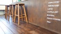 High figure wooden stool with coffee name lists in front of brown counter on the brown floor Royalty Free Stock Photo