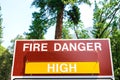 High fire danger sign informs the public that wildfires are likely. Green forest background