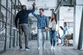 High-five. Full length of two cheerful young business people giving high-five while their colleague looking at them and smiling