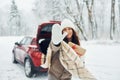 High five, gesture. Beautiful young woman is outdoors near her red automobile at winter time