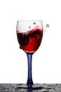 High glass of red wine in which fallen grapes