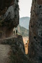 A high gorge with people taking photos of canyon on the path inside the rock.