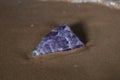 High grade rough natural Purple Auralite 23 Amethyst point from Canada on wet sand in front of the lake at sunrise