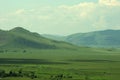 High green hills on the edge of a picturesque flat steppe overgrown with rare bushes