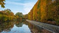 High hedge, clouds and its reflection in the pond at the Oliwa Park in the autumn scenery. Royalty Free Stock Photo